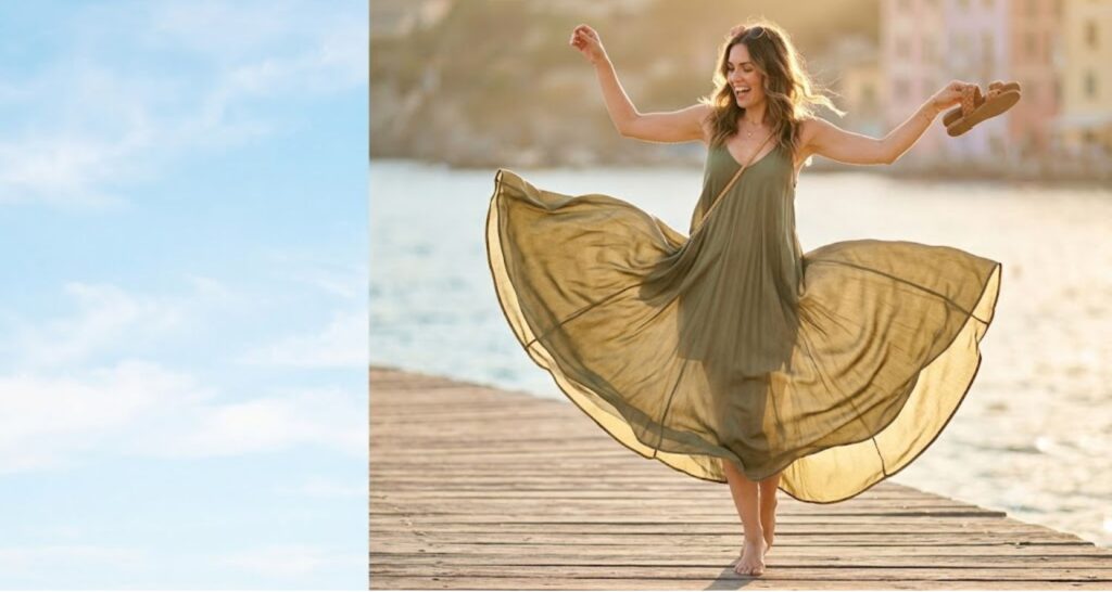 Flowy olive maxi dress flaring in motion as a woman spins on a boardwalk at golden hour