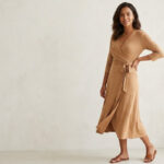 Woman wearing a camel wrap dress that defines the waist