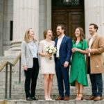 Wedding guests in semi-formal outfits standing on courthouse steps after a ceremony